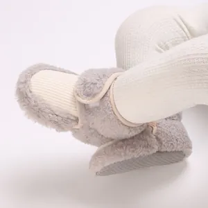 Close-up of warm gray fleece baby booties with soft non-slip soles and adjustable strap.