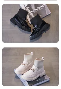 Nahaufnahme von stylischen Kinder-Sockenstiefeln in Schwarz und Creme mit Metallkettendetail.
