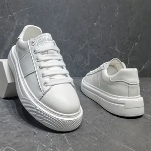 Nahaufnahme weißer Herren-Sneaker mit dicker Sohle auf grauem Marmorboden