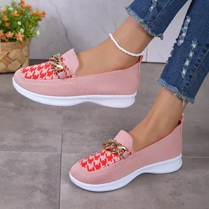 Détail de mocassins en maille rose avec chaîne métallique et motif pied-de-poule