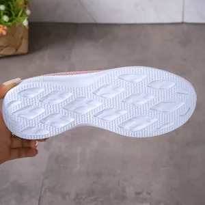Vue détaillée de la semelle extérieure blanche texturée et amortissante d'une basket en mesh rose.