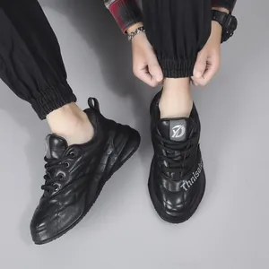 Sneakers eleganti in pelle nera da uomo con suole spesse e dettagli di cuciture trapuntate.