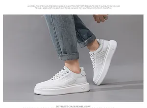Detailweergave van witte leren herensneakers met dikke zolen gedragen met jeans.