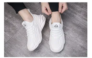 Vista dettagliata di sneaker bianche spesse e traspiranti su uno sfondo grigio