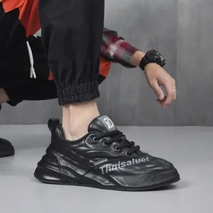Primo piano di sneakers nere in pelle con motivo trapuntato e scritta 'Thnisaluet' bianca.