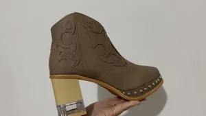 Détail de bottines marron brodées avec une bordure cloutée et talon bloc cristal