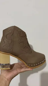 Gros plan de bottines brodées marron avec talon en acrylique et détails cloutés.