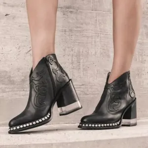 Gros plan de bottines noires brodées avec talons en cristal acrylique et rivets