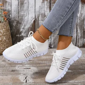 Close-up of white breathable mesh knit sneakers with laces on rustic wooden floor