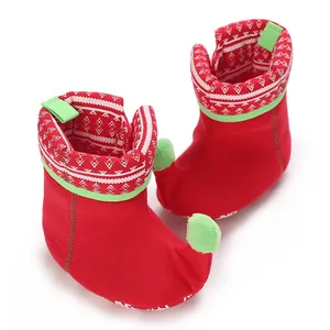 Detailed view of red elf-style baby winter boots featuring green pom-pom accents and patterns