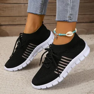 Detailed shot of stylish women's black fly-knit breathable sneakers with white soles