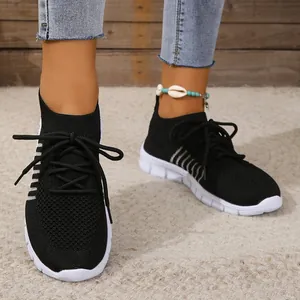 Detail view of breathable black fly-knit sneakers featuring white sole and lace-up closure
