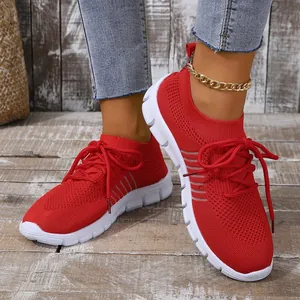 Close-up detail of stylish breathable red fly-knit sneakers worn by model with denim jeans