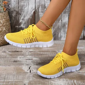 Detailed view of breathable yellow fly-knit sneakers with white flexible sole.