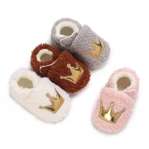 Close-up view of four colors of warm plush baby booties featuring golden crown appliques