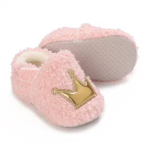 Close-up of pink fuzzy baby winter booties with soft anti-slip sole and gold crown detail
