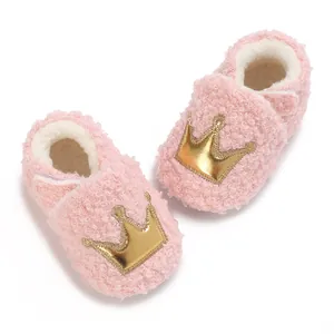 Close-up detail of pink fleecy baby booties featuring a golden crown and soft white lining