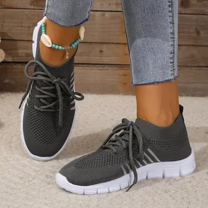 Close-up of grey breathable knitted mesh sneakers with white soles and lace-up design.