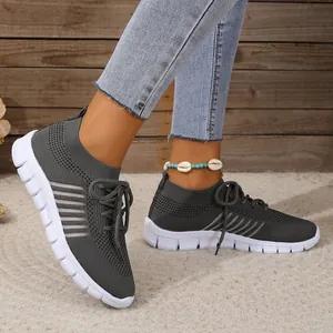 A detailed side view of breathable dark grey mesh knit sneakers worn by a model