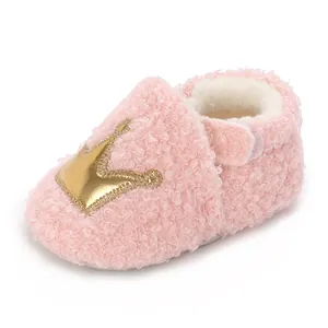 Close-up detail of soft pink fuzzy baby bootie featuring a golden crown and warm lining