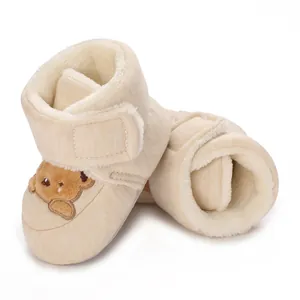 Primer plano de botas de invierno beige para bebé con forro de felpa y bordado de oso.