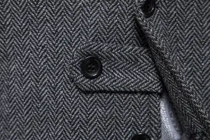 Dettaglio macro del tessuto in tweed a spina di pesce grigio su un gilet da uomo