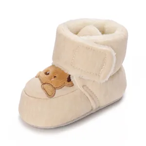 Close-up of warm cream baby winter bootie with cute bear embroidery and fur lining