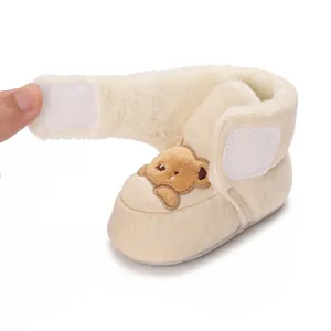 Close-up of baby winter booties showing thick faux fur lining and bear embroidery.