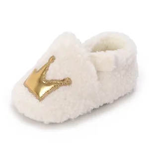 Detailed view of soft white sherpa baby booties featuring a golden crown and velcro strap