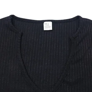 Detailed close-up view of the deep V-neckline and fabric tag of a black ribbed knit shirt