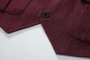 Primo piano dettagliato del tessuto in tweed a spina di pesce rosso e bottone nero su gilet.