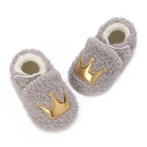 Macro detail of baby winter fleece shoes with gold crown patch and warm plush lining.