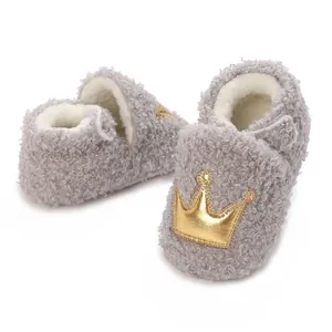 Close-up of grey fuzzy baby shoes featuring gold crown patch and warm fleece lining