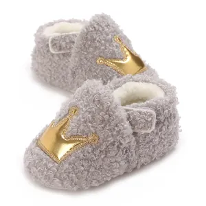 Close-up of fuzzy grey baby walker shoes with golden crown patch and warm fleece lining.