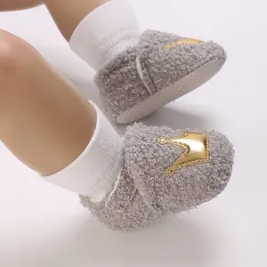 Macro view of grey fleece baby booties featuring a gold crown motif and soft sole.