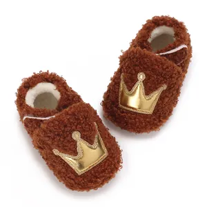 Detailed macro view of soft brown teddy fleece baby booties featuring a gold crown design