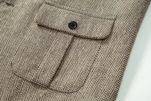 Dettaglio macro della tasca di un gilet in lana spigata marrone con bottone nero rétro