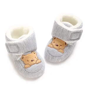 Close-up of baby walking shoes featuring soft grey fabric and a cute cartoon bear design.