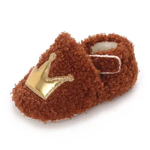 Soft brown fuzzy sherpa baby booties featuring a shiny golden crown patch detail