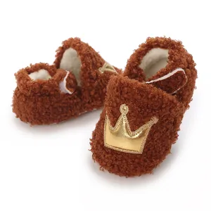 Macro view of warm brown fuzzy baby booties featuring a decorative golden crown patch