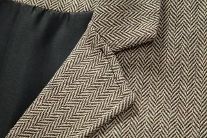 Dettaglio ravvicinato della trama in tweed a spina di pesce marrone del gilet vintage.