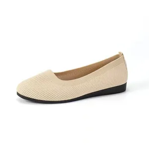 Detailed view of beige knitted flat shoes with breathable mesh and flat black sole.
