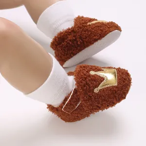 Detail of brown fleece infant pre-walker shoes with golden crown patch for winter.