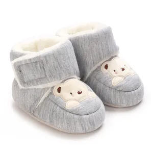 Close-up of grey baby winter booties with cute bear patch and soft white fleece lining.