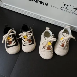 Detail of kids casual soft-sole sneakers in black and beige with thick rope laces