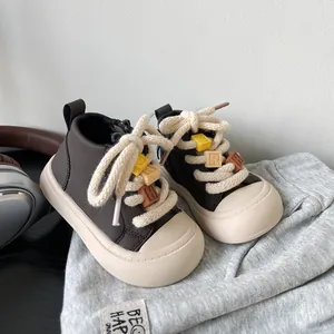 Close-up of toddler brown high-top board shoes with colorful letter blocks on laces.