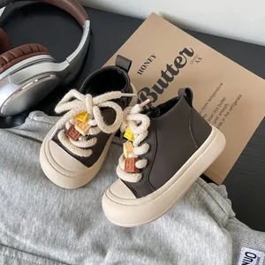 Close-up detail of brown toddler high-top sneakers with chunky laces and alphabet beads.