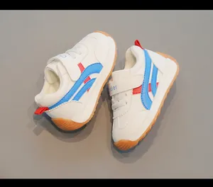 Primo piano di sneakers bianche per bambini con strisce blu e rosse e chiusura a strappo