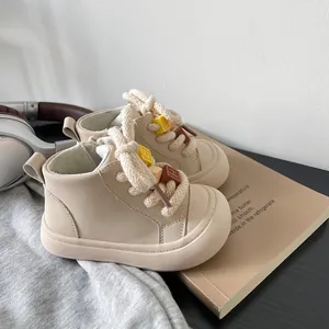 Close-up detail of beige toddler walking boots with thick rope laces and decorative blocks