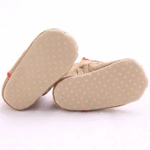 Macro detail view of anti-slip dotted soles on warm brown fleece baby booties for infants
